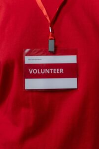 A close-up of a volunteer name tag hanging on a red lanyard, symbolizing community service.